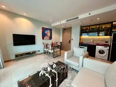 Modern living room with open kitchen, featuring sleek furniture and appliances.