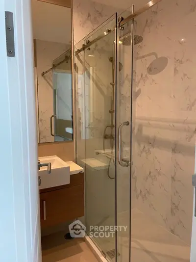 Modern bathroom with glass shower enclosure and sleek vanity in a contemporary apartment.