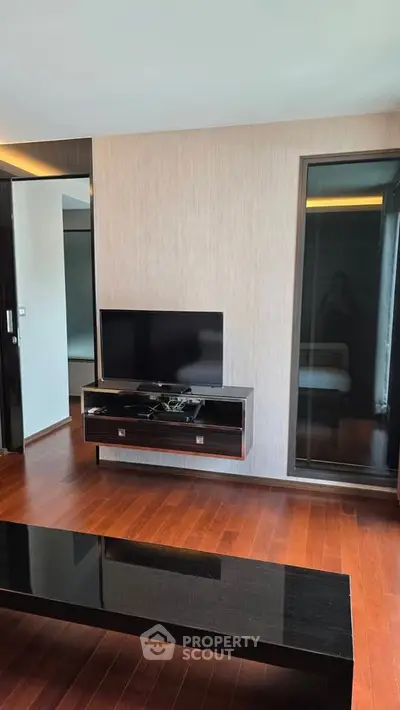 Modern living room with sleek TV stand and wooden flooring in a stylish apartment.