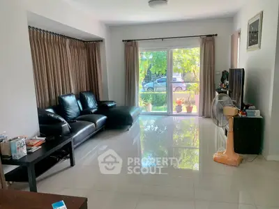 Spacious living room with modern black leather sofa and large window view.