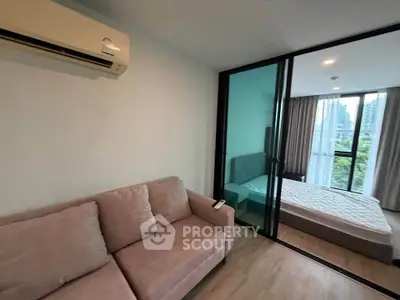 Modern apartment with cozy living room and bedroom separated by glass sliding door, featuring city view.
