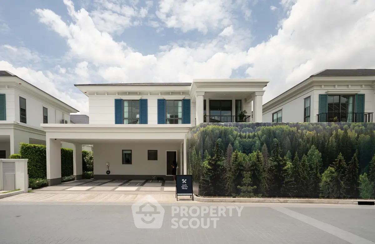 Luxurious modern house with elegant facade and spacious driveway, surrounded by lush greenery and blue skies.