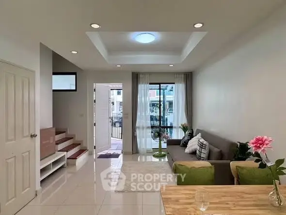 Modern living room with stylish decor and natural light, featuring a cozy sofa and elegant staircase.