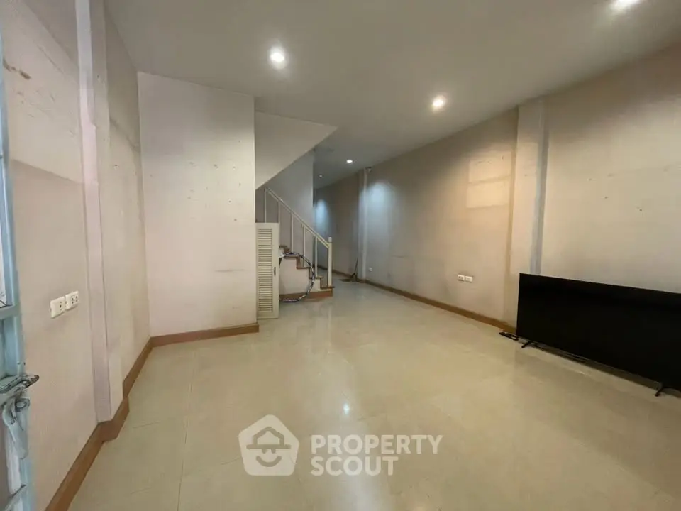 Spacious unfurnished room with staircase and modern lighting, ideal for customization.