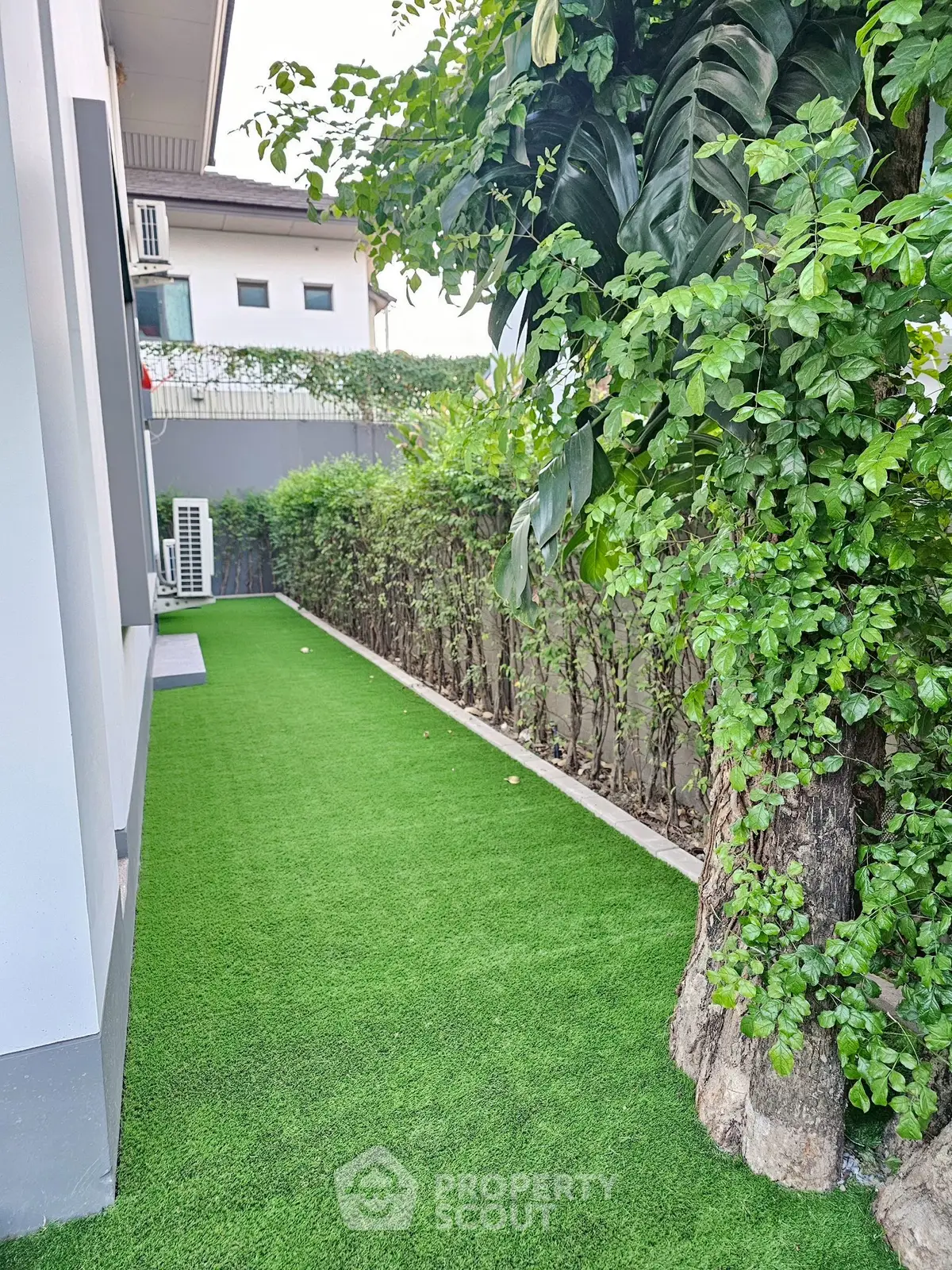 Charming garden area with lush greenery and artificial grass, perfect for relaxation and outdoor activities.