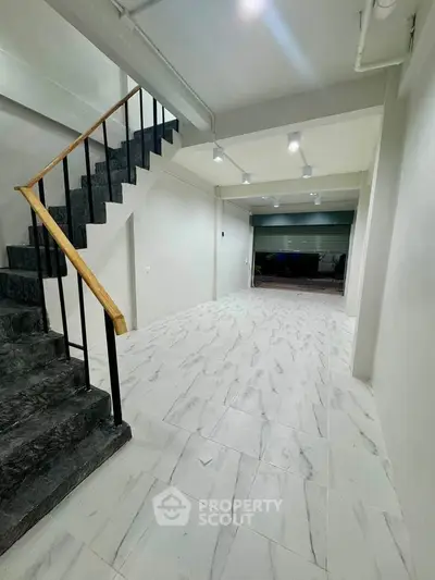Spacious modern interior with marble flooring and sleek staircase, ideal for versatile real estate opportunities.