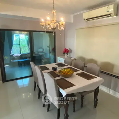 Elegant dining room with chandelier and air conditioning, featuring a stylish table setting and garden view.
