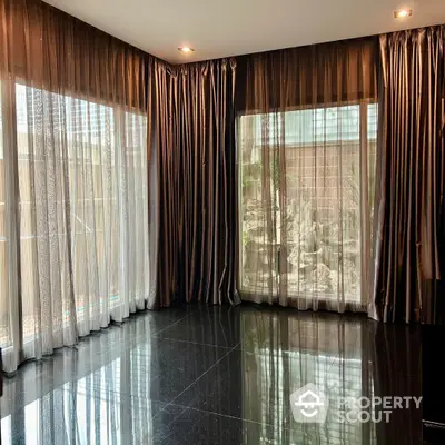 Spacious living room with elegant floor-to-ceiling curtains and glossy black tile flooring.