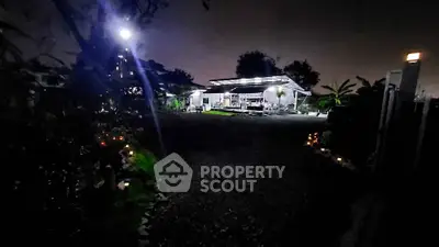 Charming night view of a modern house with lush garden and ambient lighting.