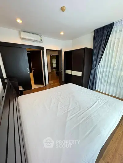 Spacious bedroom with modern furnishings and large window for natural light.