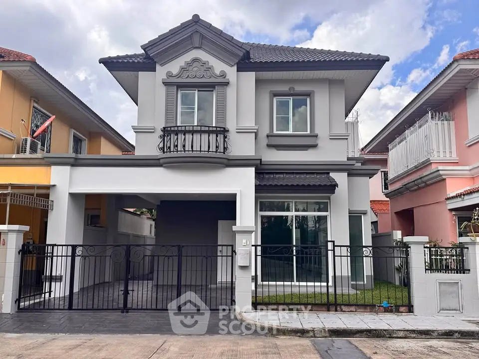 Elegant two-story house with classic architectural details and gated driveway in a suburban neighborhood.