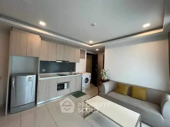 Modern open-layout living room with kitchen, featuring sleek appliances and cozy seating area.