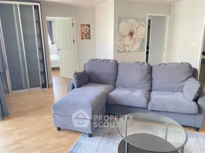 Spacious living room with modern gray sofa and glass coffee table, featuring elegant decor and wooden flooring.
