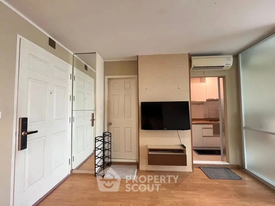 Modern apartment interior with wall-mounted TV and compact kitchen
