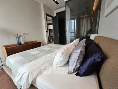 Luxurious bedroom with modern decor and glass partition, featuring elegant bedding and stylish furniture.