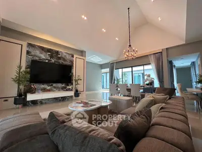 Luxurious living room with vaulted ceiling, elegant chandelier, and spacious seating area in modern home.