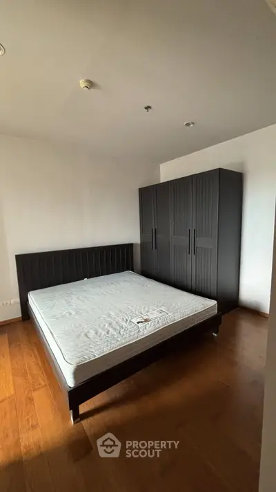 Spacious bedroom with wooden flooring and modern wardrobe, perfect for a cozy living experience.