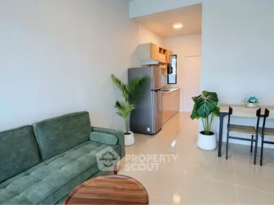Modern open-plan living room with green sofa and sleek kitchen area.