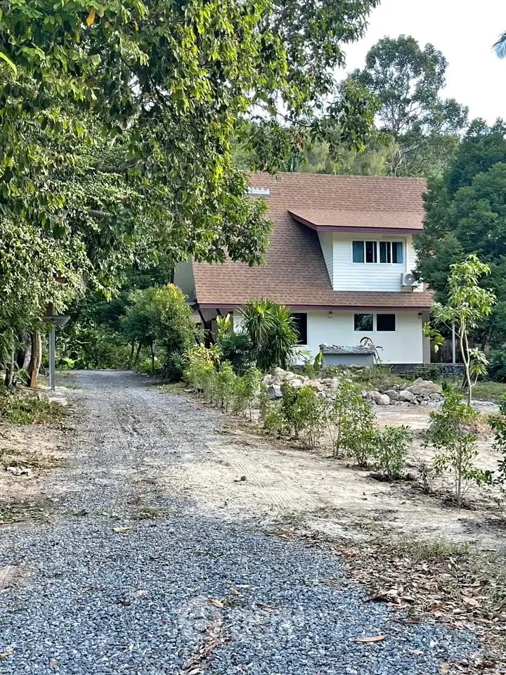Charming countryside house with lush greenery and gravel driveway, perfect for serene living.