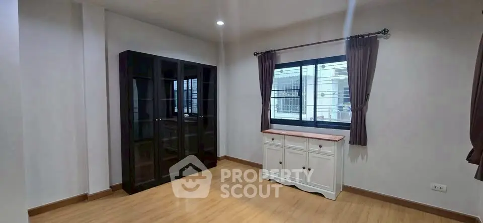 Spacious room with wooden flooring and large window for natural light