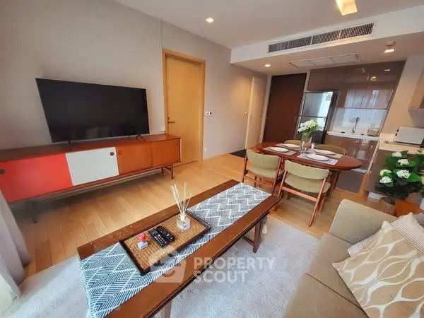 Modern living room with stylish decor and dining area, featuring a flat-screen TV and cozy seating.
