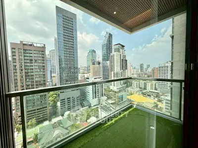 Stunning cityscape view from a modern high-rise balcony with lush green flooring.