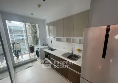 Modern kitchen with sleek cabinetry and appliances, featuring a washing machine and balcony access.