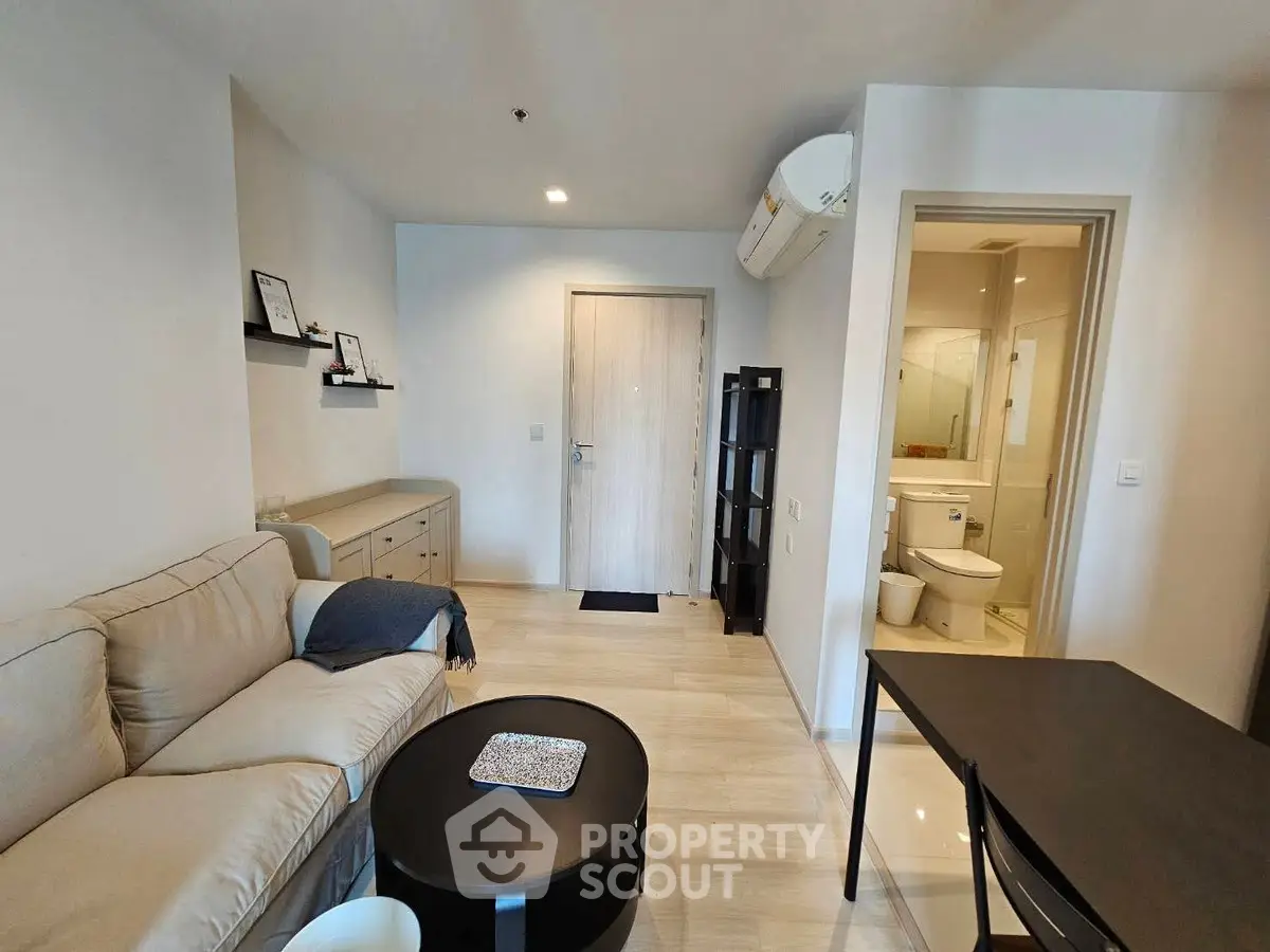 Modern living room with cozy sofa and open view to bathroom, ideal for urban living.