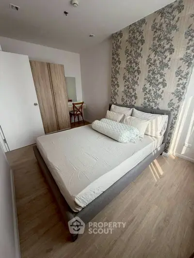Cozy bedroom with stylish wallpaper and natural light, perfect for relaxation.