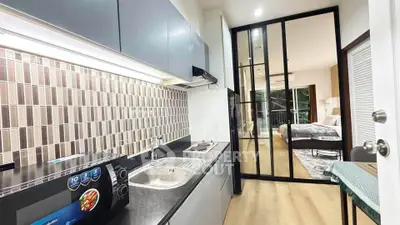 Modern apartment kitchen with sleek design and open layout leading to a cozy bedroom.