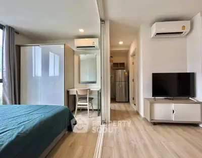Modern bedroom with mirrored closet, air conditioning, and sleek TV setup in a stylish apartment.