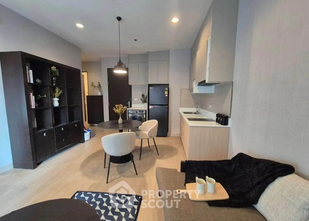 Modern living room with open kitchen, stylish furniture, and cozy decor in a contemporary apartment.