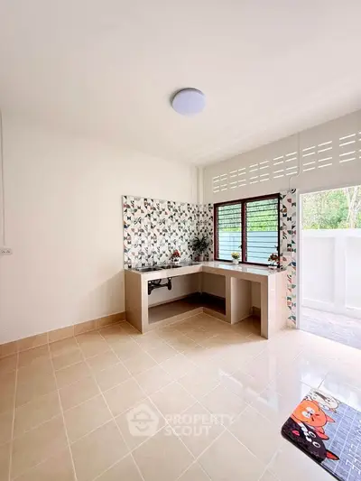 Bright kitchen with open layout and modern backsplash, featuring large windows and tiled flooring.