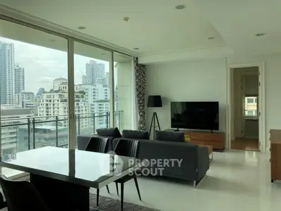 Modern living room with city view, featuring sleek furniture and large windows in a high-rise apartment.
