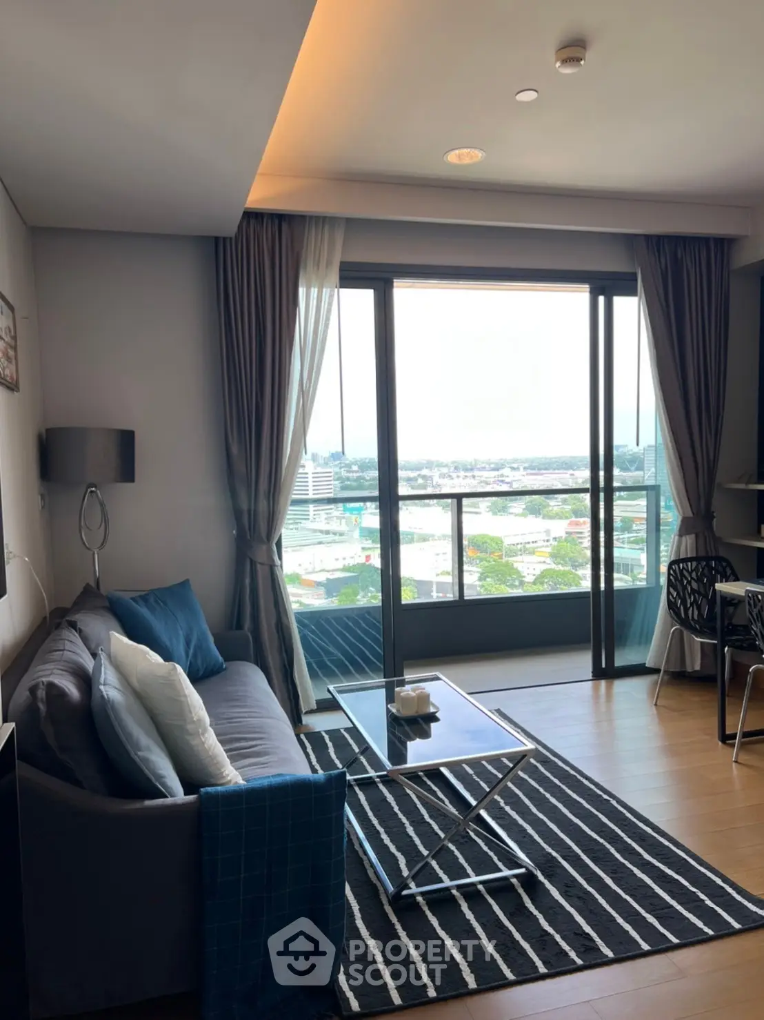 Modern living room with balcony and city view, featuring stylish decor and natural light.