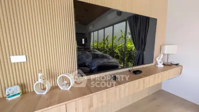 Modern living room with sleek wooden paneling and large TV, overlooking lush greenery.