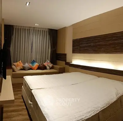 Spacious modern bedroom with twin beds and cozy seating area