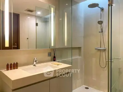 Modern bathroom with glass shower and sleek vanity in luxury apartment.