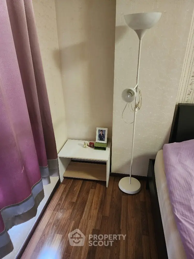 Cozy bedroom corner with elegant floor lamp and modern bedside table, featuring rich wooden flooring and soft drapery, perfect for restful nights.