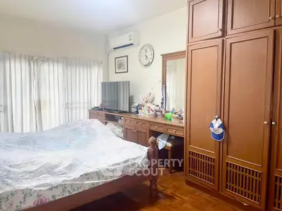 Cozy bedroom with wooden furniture and natural light, perfect for relaxation and comfort.