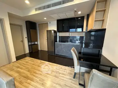 Modern apartment interior with sleek kitchen and dining area, featuring wooden flooring and contemporary design.