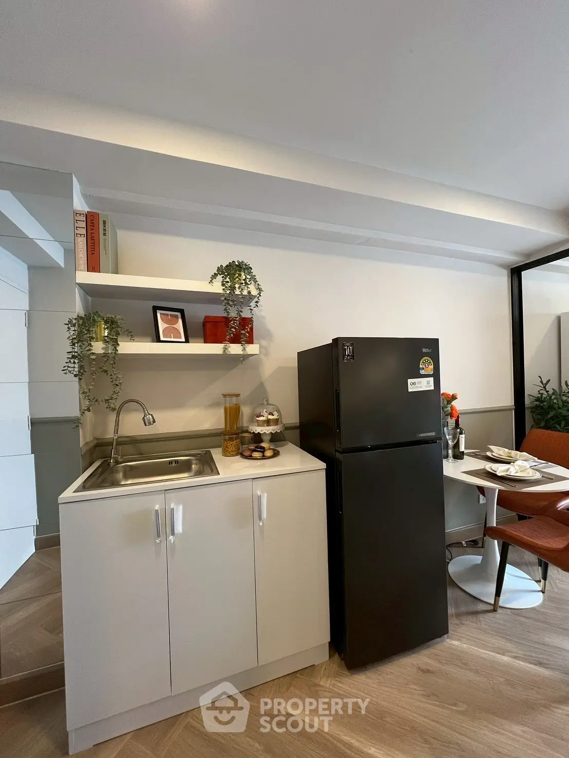 Modern kitchen with sleek black fridge and compact dining area, perfect for urban living.