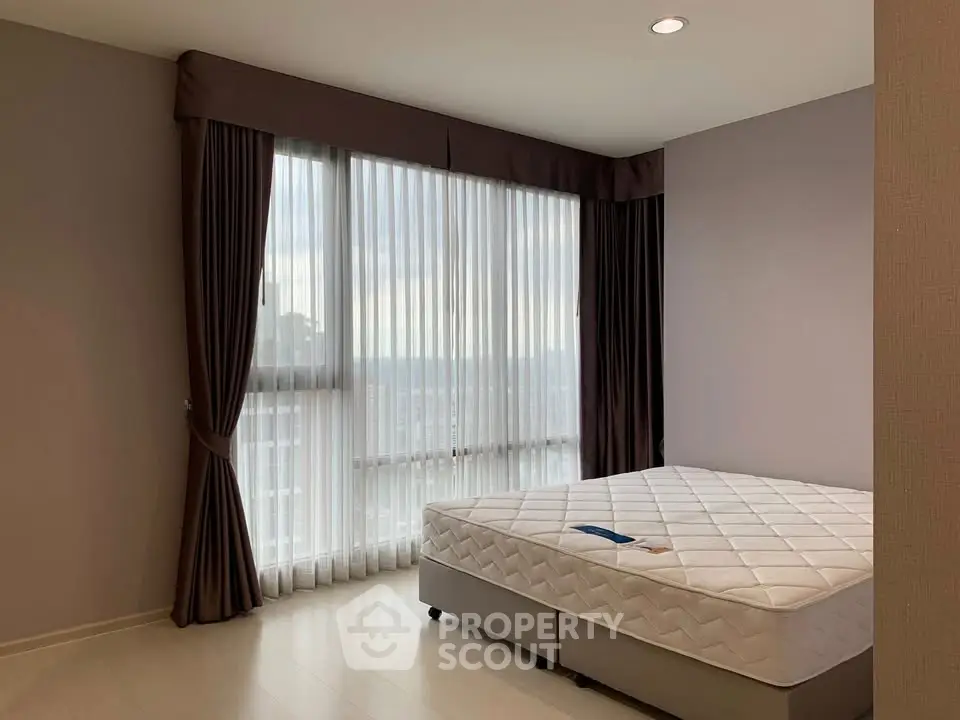 Spacious bedroom with large window and elegant curtains in modern apartment