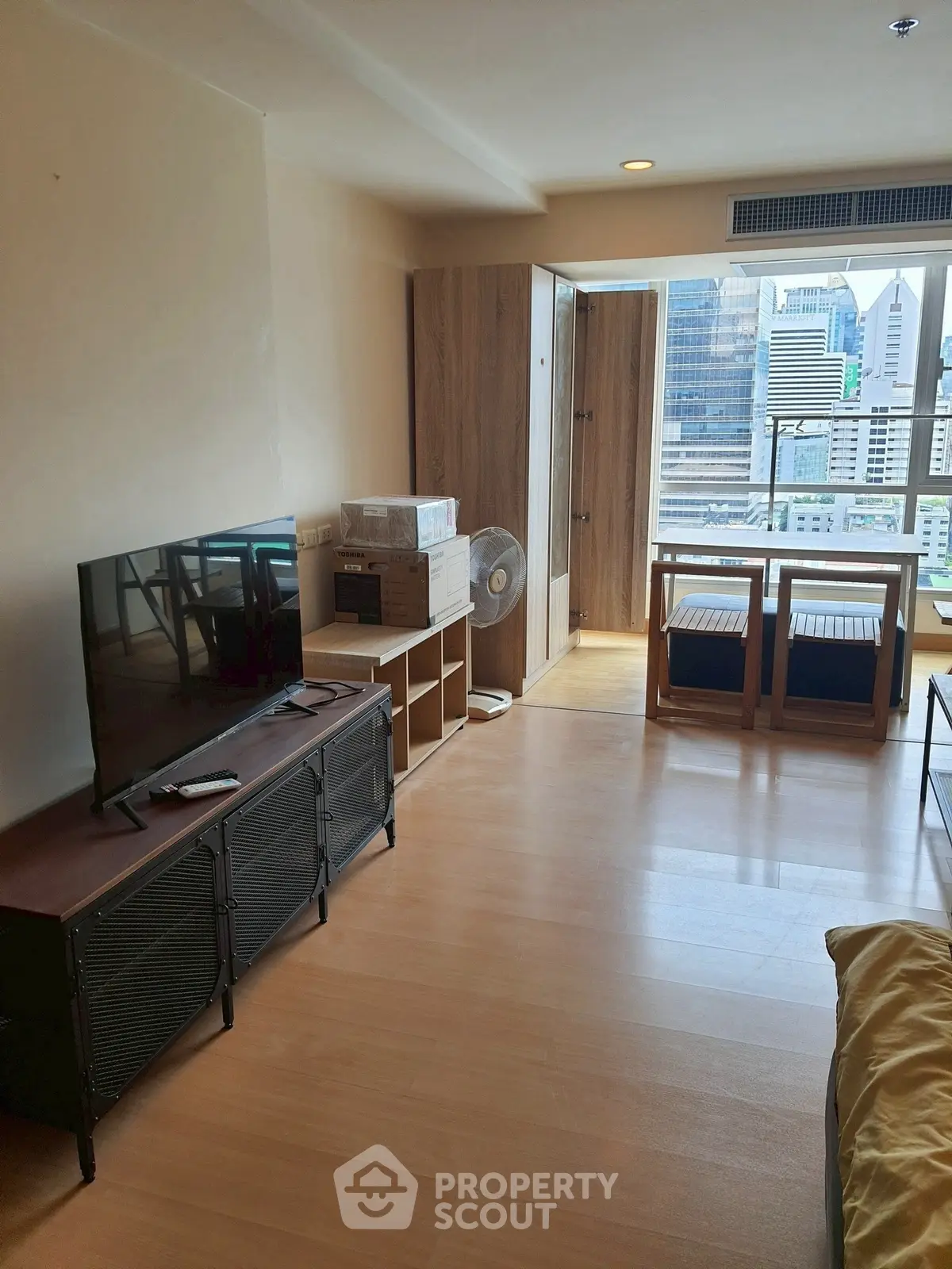 Modern living room with city view, wooden flooring, and sleek furniture.
