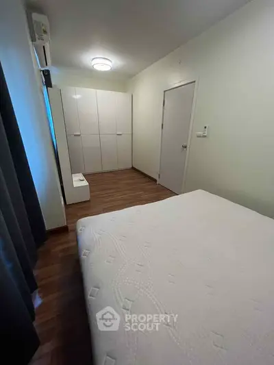 Modern bedroom with wooden flooring and sleek white wardrobe