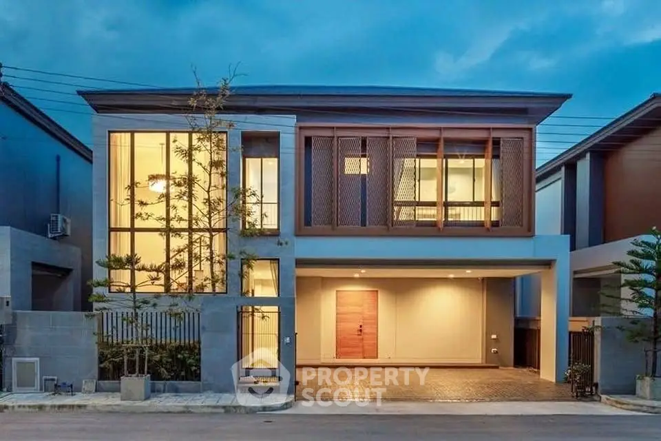 Modern two-story house with large windows and elegant facade at dusk.