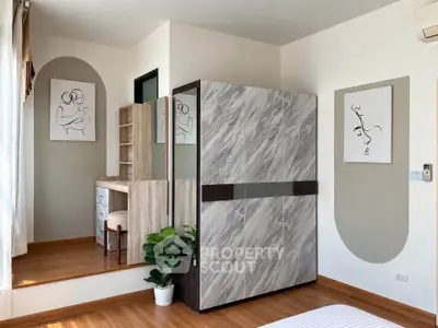 Modern bedroom with stylish decor and wooden flooring, featuring a unique wardrobe and artistic wall art.