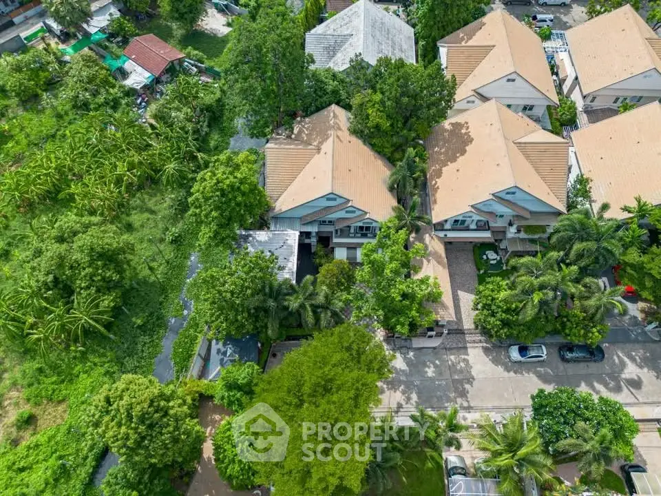 Aerial view of suburban houses with lush greenery and spacious driveways.