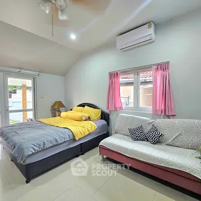 Cozy bedroom with modern decor and natural light, featuring a comfortable bed and stylish sofa.