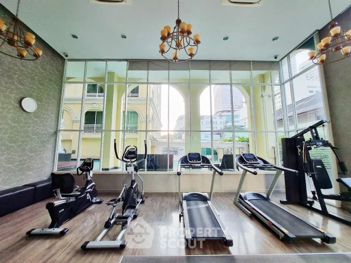 Spacious gym with modern equipment and large windows offering city views